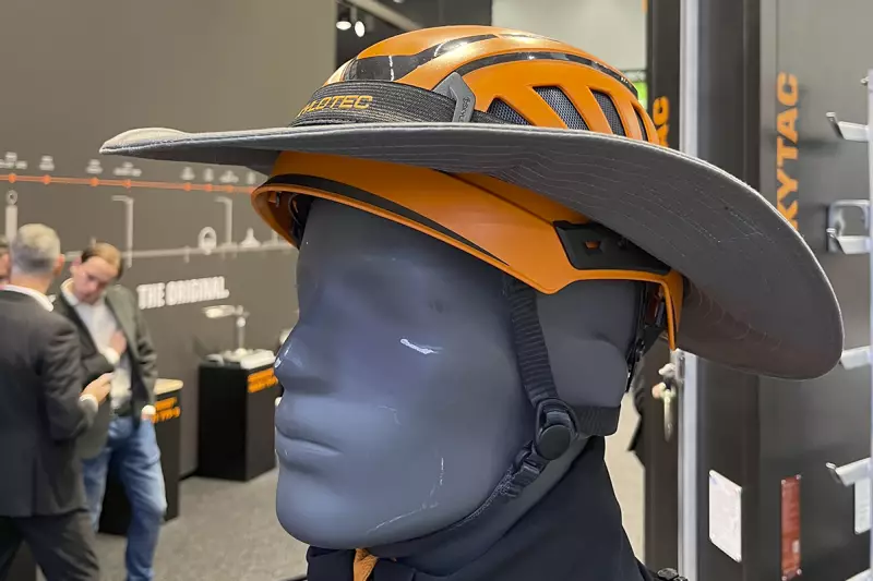 Es könnte so einfach sein. Skylotec zeigte, wie sich bei einem Helm der wichtige Sonnenschutz mit einem Regenschutz verbinden lässt. Der Hutaufsatz wird mit Klettband seitlich fixiert, um bei Regen ablaufendes Wasser nach hinten abzuleiten. Quelle: Treffpunkt.Bau