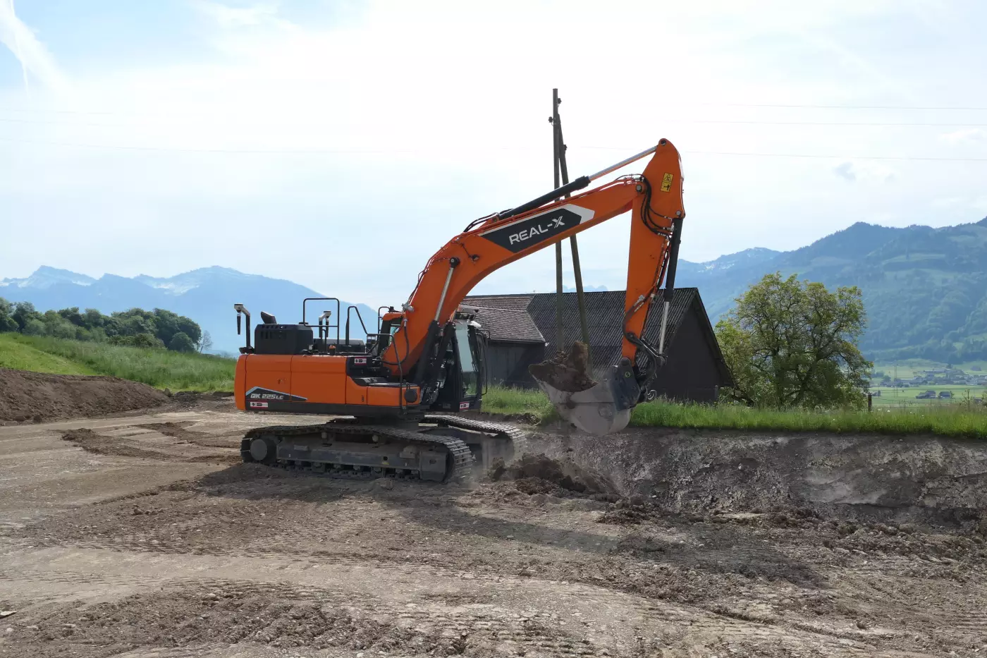 Prächtige Kulisse: Der autonom arbeitende DEVELON-Real-XKettenbagger DX225LC beim Praxiseinsatz im ehemaligen Steinbruch der KIBAG im schweizerischen Tuggen.