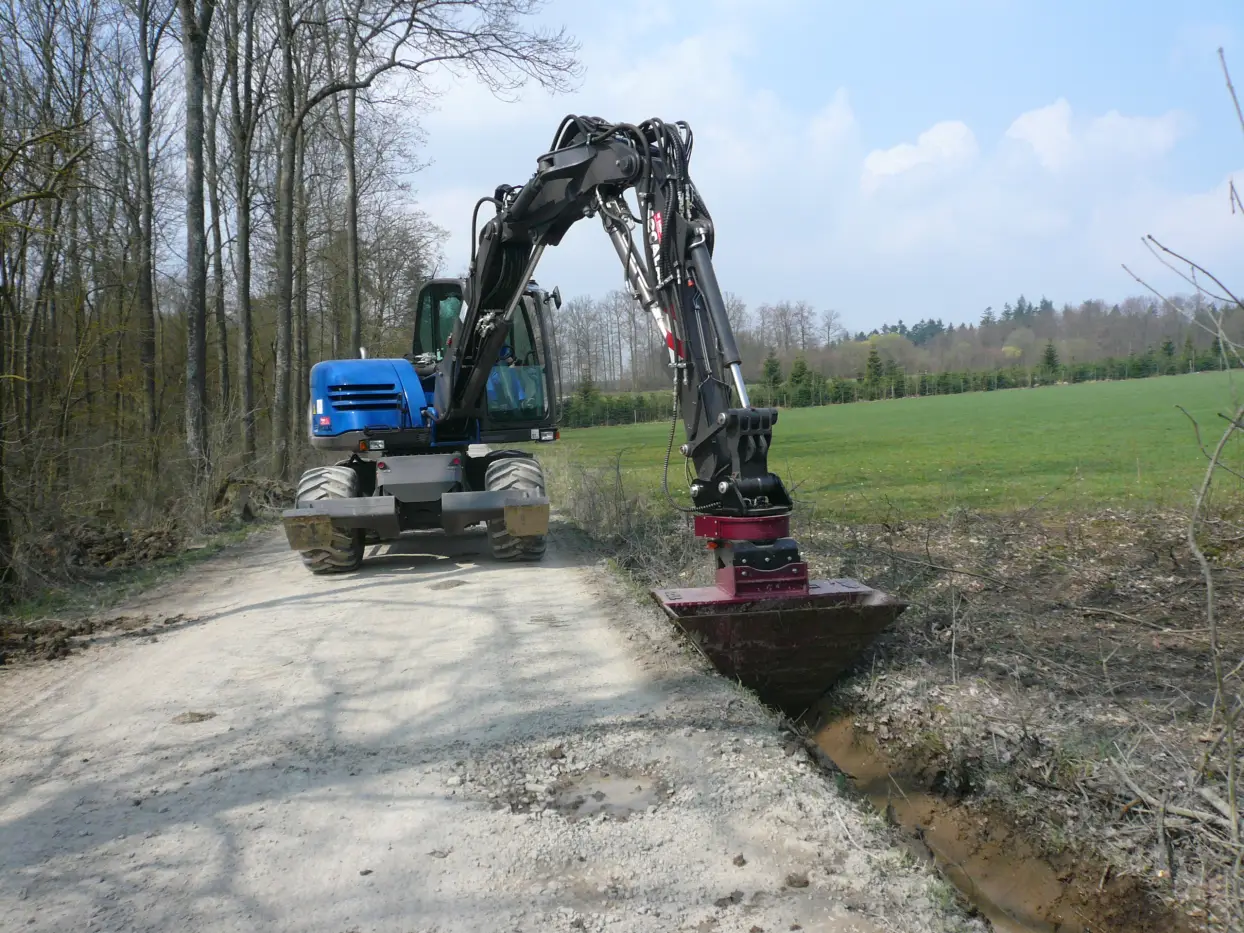 Die Kombination von RotoTop und VarioLöffel sorgt für den effizienten Bau von Gräben neben Straßen und Wegen – als wichtige Hochwasserschutzmaßnahme.

