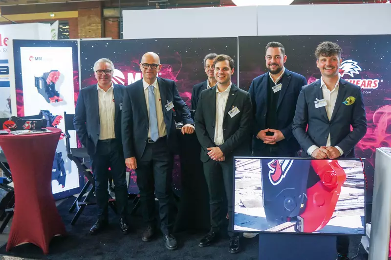 Wenn die Teams aus Deutschland und Italien zusammentreffen, ist die Freude groß: Das MBI Team zeigte in Berlin seine Anbaugeräte für Abbruch- und Recyclingarbeiten. Dazu gehören unter anderem Betonbrecher, Kombischneider, rotierende und feste Pulverisierer, Schrottscheren und Sortiergreifer. Quelle: Treffpunkt.Bau
