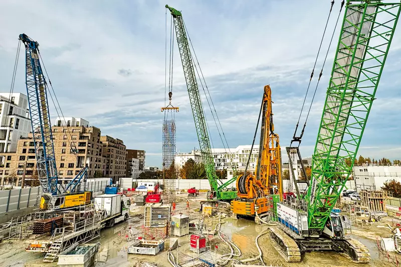 Drei Sennebogen-Krane und Seilbagger auf der Baustelle „Les Caboeufs” in Gennevilliers: Der 6130HD mit Schlitzwandgreifer im Tandem mit einer Hydrofäse, der 6140HD beim Schwerlasthub und der Raupenkran 3300 beim Verheben von Bewehrungskörben. Quelle: Sennebogen