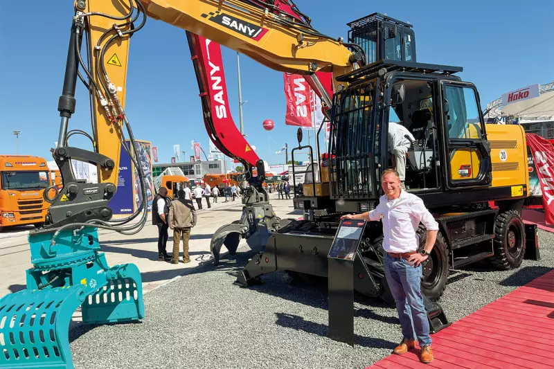 Tim Hein, Marketingmanager bei Sany, vor dem SY175W Mobilbagger. Die Maschine gilt als besonders robust und standfest. Der ZF-Antriebs-strang mit einer Bodenfreiheit von 360 mm und permanentem Allradantrieb meistert auch die härtesten Bedingungen. Quelle: Treffpunkt.Bau