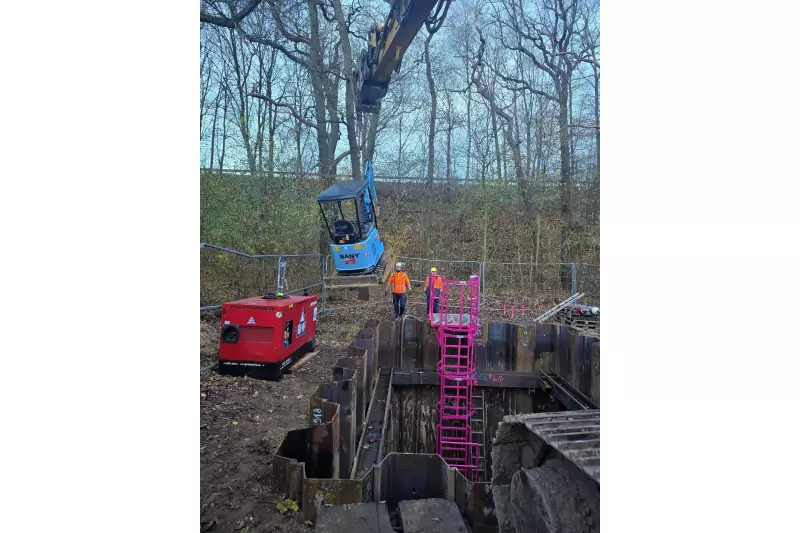 Der elektrische Minibagger SY19E wird kontrolliert in die Baugrube abgelassen. Geladen über den externen Stromgenerator am Grubenrand. 

