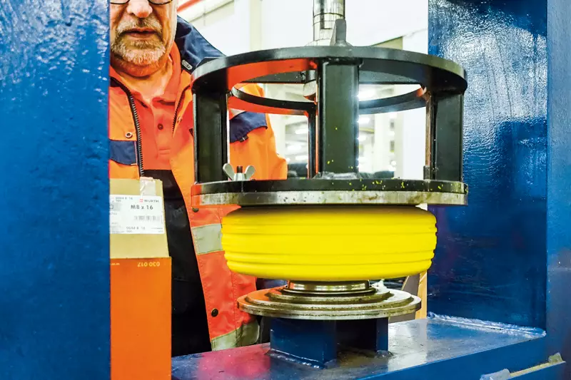 Mit der hydraulischen Presse wird der Vollgummireifen präzise auf die Felge aufgebracht. Der Montagevorgang erfordert hohen Pressdruck und sorgt für einen formschlüssigen Sitz – entscheidend für den sicheren Einsatz in engen Arbeitsumgebungen. Quelle: Treffpunkt.Bau