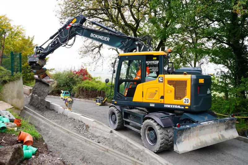 Mobilbagger beim Wegebau in Waldenburg. Der Fahrer muss Splitt feinfühlig zur Vorbereitung der neuen Gehwege an einer Pumpstation verteilen.
