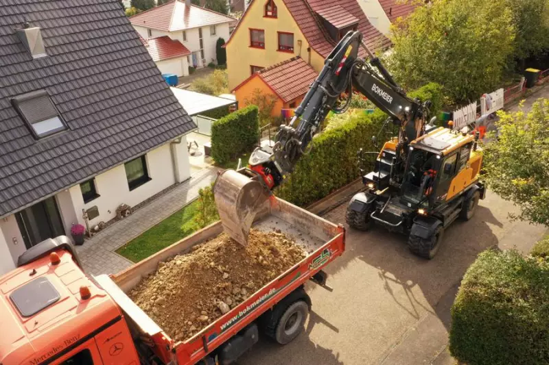 Sanierung von Abwasserkanal und Hausanschlüssen in Röttingen. Nur Kurzheckbagger schaffen die LKW-Beladung in dieser typischen schmalen Wohnstraße.
4. Deutlich erkennbar ist das Kurzheck, welches innerhalb der Gerätekontur schwenkt.

