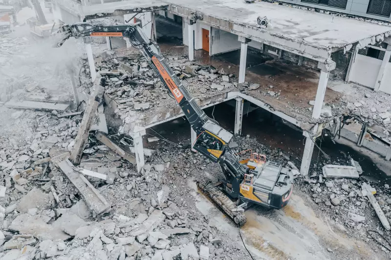 Bagger mit Abbruchausrüstung, ausgefahrenem Teleskopfahrwerk und hochgefahrener und gekippter Kabine