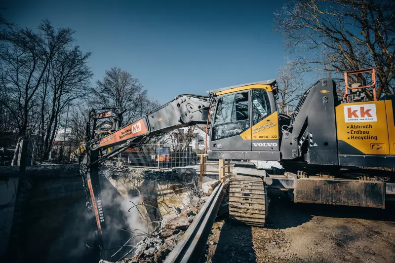 Bagger mit Abbruchausrüstung und ausgefahrenem Teleskopfahrwerk beim Tiefbau