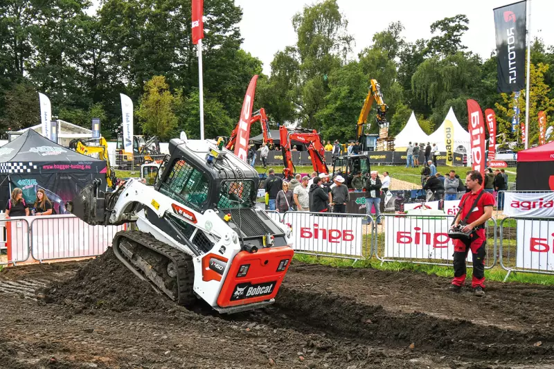 Ganz entspannt vom Pistenrand bedient der Fahrer den ferngesteuerten Bobcat. Auf dem gut besuchten Freigelände präsentierten die Hersteller ihre Neuheiten und Technologien in Aktion. Quelle: Treffpunkt.Bau
