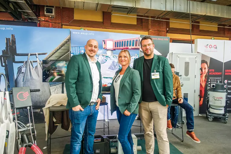 Asup informierte über Lösungen für die verschärften regulatorischen Anforderungen im Bereich Asbestsanierung. Marcel Gomula, Lea Malkovsky und Timo Gaulke (v. l.) präsentierten u. a. die neuesten Gebläsefiltersysteme, die auch bei hohen Außentemperaturen angenehmen Tragekomfort und maximale Sicherheit bieten. Quelle: Treffpunkt.Bau