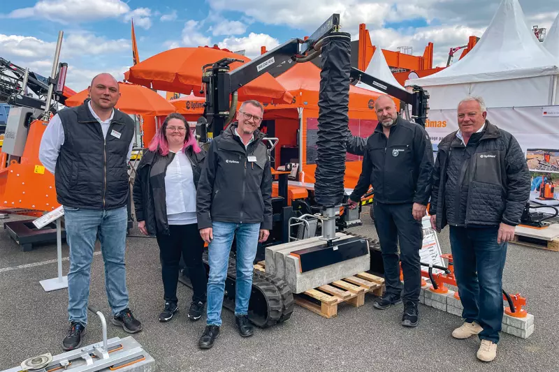 Das Optimas-Team versammelte sich für das Foto vor dem Vacu-Pallet-Mobil. Seit der Bauma 2022 ist es auch mit Elektromotor verfügbar. Es kann Paletten mit einem Gewicht von bis zu 1.600 kg und einer Breite von bis zu 1,32 m transportieren und verlegen. Quelle: Treffpunkt.Bau