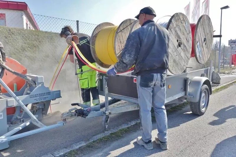 Ein Mitarbeiter kontrolliert, ob die Kabel richtig in der Fuge liegen, ein zweiter überprüft, ob sie sauber von der Trommel rollen.