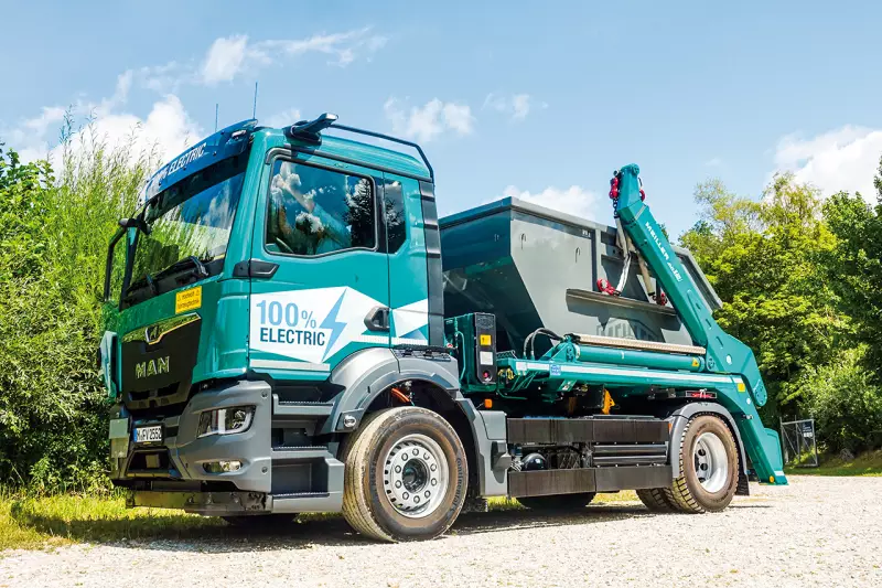 Der MAN eTGS 4x2 mit Meiller Absetzkipper eignet sich mit seinem kompakten Radstand besonders gut für enge Baustellen und städtische Einsatzgebiete. Mit vier Batteriepaketen und einer nutzbaren Gesamtkapazität von 320 kWh bietet er eine Reichweite von bis zu 450 km. Quelle: Treffpunkt.Bau