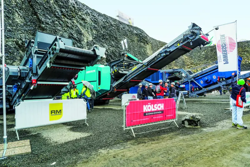 Jürgen Kölsch und C. Christophel traten mit einem gemeinsamen Stand auf, um wirtschaftlich aufeinander abgestimmte Prozessketten für den Steinbruch vorzuführen. Ein Highlight war der 80 t schwere Backenbrecher Powerscreen Premiertrak 600 XL, der dank aktiver Vorsiebung Feinkorn frühzeitig ausschleust, um Verschleiß und Kraftstoffverbrauch deutlich zu senken. Ihre steinexpo-Premiere feierte die Prallbrechanlage Hazemag Dynarox I-120 mit hydraulisch ausweichenden Prallwerken als geschlossenes Überlastsystem. Quelle: Treffpunkt.Bau