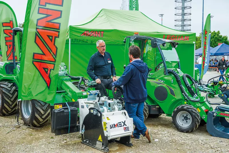 Auf der IFAT zeigte Avant Tecno Deutschland kompakte Trägergeräte mit vielseitiger Anbauausrüstung. Oliver Bonn (links), Verkauf Außendienst, ist hier neben einem etwas verdeckten Avant 860i mit selbstnivellierender Simex-Straßenfräse der PL-Baureihe zu sehen. Der 860i bietet 1.900 kg Hubkraft, 3.500 mm Hubhöhe und 42 kW Motorleistung. Quelle: Treffpunkt.Bau