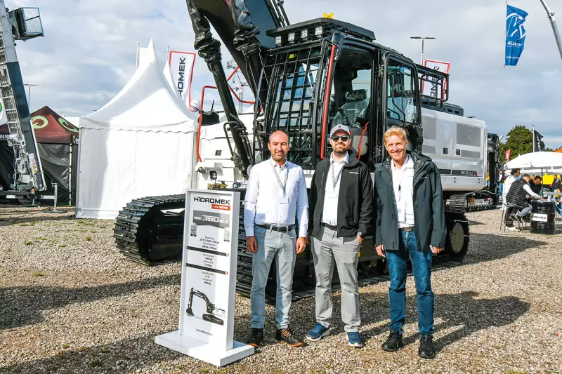 Hidromek zeigte Größe. Marketing Manager Emrah Aksongur und Anil Bingül mit Bernd Mair von Treffpunkt.Bau (v. l.) vor dem 40-Tonner HMK360 NLC, dem mächtigsten der elf Ausstellungsstücke des Herstellers aus Ankara auf der NordBau. Quelle: Treffpunkt.Bau