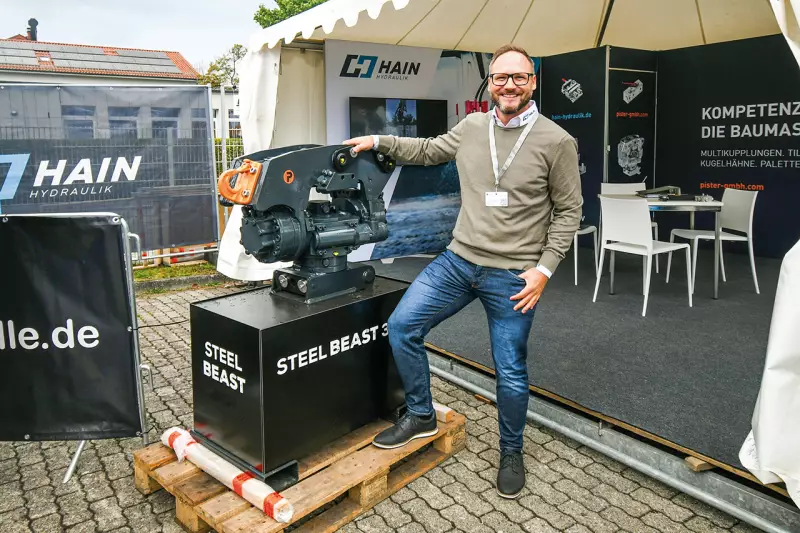 Christian Hain von Hain Hydraulik mit dem neuen „Baby“-Beast. Pister stellt seinem Steel Beast-Tiltrotator für Trägergeräte von 7–10 t eine kleinere Version für Maschinen bis 7 t zur Seite. Dank schlanker Bauweise eckt das robuste Gerät auch in engen Gräben nicht an. Quelle: Treffpunkt.Bau