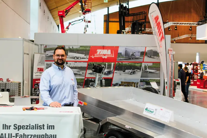 Tima stellte seine robusten Aluminium-Pkw-Anhänger und Aufbauten für den sicheren Maschinentransport vor. Im Fokus standen leichte Tandem-Tieflader, die mit ihren hohen Nutzlasten, flachen Auffahrwinkeln und integrierten Zurrsystemen speziell auf das Be- und Entladen von Arbeitsbühnen, Baugeräten und Flurförderzeugen ausgelegt sind. Bastian Wittmershaus zeigte uns auch die patentierten Drehzurrbügel zur Optimierung von Sicherheit und Ladeeffizienz im Transportalltag. Quelle: Treffpunkt.Bau