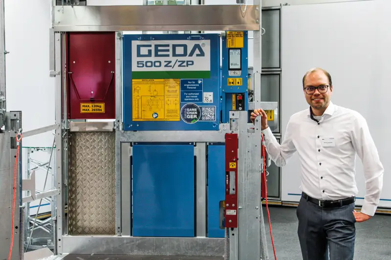 Im Mittelpunkt bei Geda stand die Transportbühne 500 Z/ZP. Das Zwei-in-Eins-System verbindet einen Materialaufzug mit einer zugelassenen Transportbühne für bis zu fünf Personen sowie Lasten bis zu 850 kg. Dank flexibler Bühnenvarianten, des bewährten Uni-X-Mast-Systems und einer Förderhöhe von bis zu 100 m erweist sich der Geda 500 Z/ZP als rentabler Allrounder für unterschiedlichste Baustellenanforderungen, wie Michael Hausmann erläuterte. Quelle: Treffpunkt.Bau