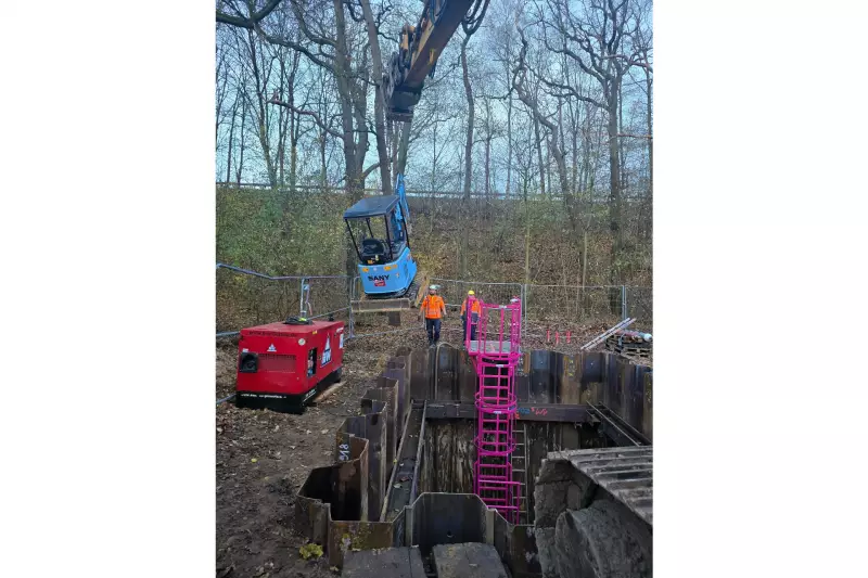 Der elektrische Minibagger SY19E wird kontrolliert in die Baugrube abgelassen. Geladen über den externen Stromgenerator am Grubenrand.