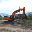 Prächtige Kulisse: Der autonom arbeitende DEVELON-Real-XKettenbagger DX225LC beim Praxiseinsatz im ehemaligen Steinbruch der KIBAG im schweizerischen Tuggen.