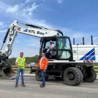XXL-Schlüsselübergabe mit Hartmut Horn (rechts), Geschäftsführer der BHS-Baubetriebe, Matthias Lietsch (links), Verkaufsrepräsentant der Zeppelin Niederlassung Dresden, und Baggerfahrer Nico Lehmann in der Kabine.
